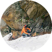 Advanced Wilderness Survival. Picture of a man making a fire in the snow.